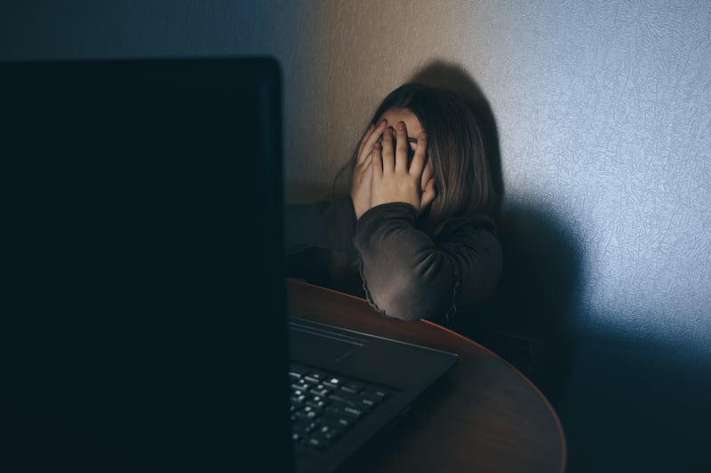 Teenager girl suffering internet cyber bullying scared and depressed cyberbullying. Image of despair girl humilated on internet by classmate. Young teenage girl crying in front of the laptop.